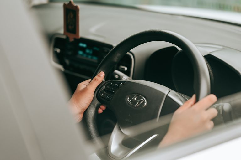 Close-up view of hands holding the steering wheel inside a car.